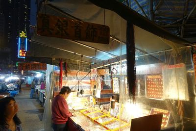 People at illuminated market in city at night