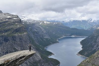 Woman standing at mountain edge against sky