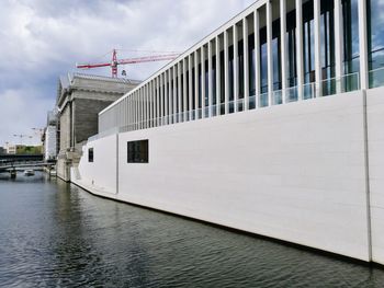 Bridge over river amidst buildings in city against sky