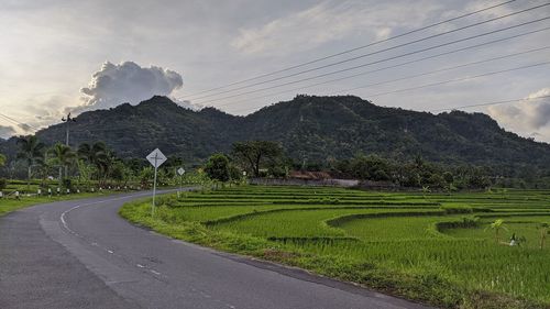 Scenic view of road by mountains against sky