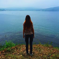 Rear view of woman standing in front of sea