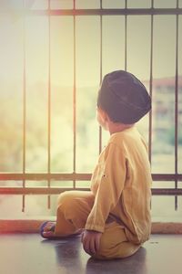 Boy sitting on floor by metal grill