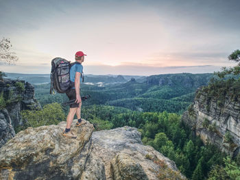 Professional photographer with tripod on cliff and thinking. dreamy landscape within sunrise. 