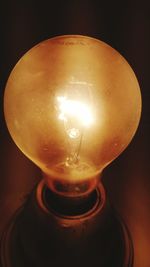 Close-up of illuminated light bulb against black background