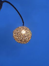 Low angle view of illuminated lamp against blue sky