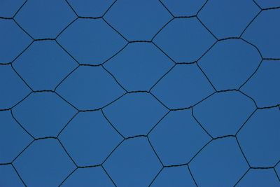 Low angle view of blue sky seen through chainlink fence