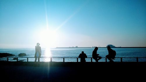 Silhouette people on beach against clear sky during sunset