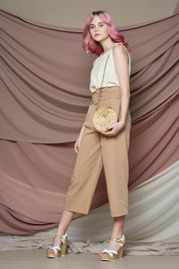 Portrait of young woman standing against wall