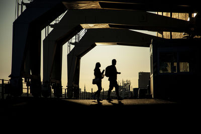 Silhouette people standing by building in city