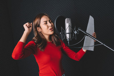 Young woman singing song in recording studio