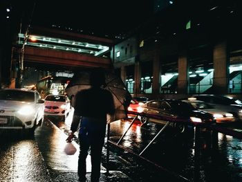 Man standing on wet street at night