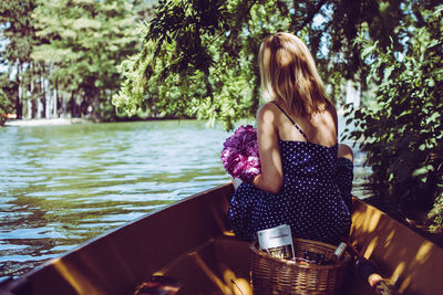 Woman sitting in boat on lake against trees