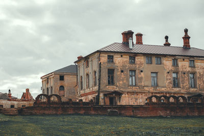 View of old building by river against cloudy sky