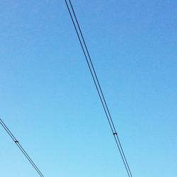 Low angle view of electricity pylon against blue sky