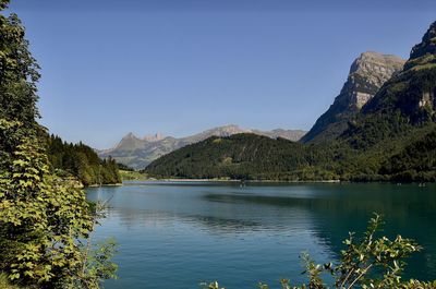 Scenic view of lake and mountains against clear blue sky