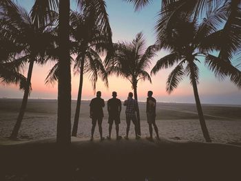 Silhouette people at beach against sky during sunset