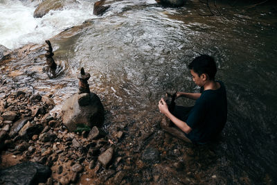 A boy stacking stones in a flowing stream