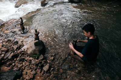 Side view of boy sitting on rock