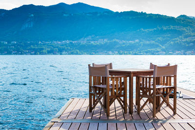 Chairs and table by sea against mountains