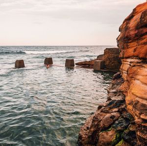 Man swimming in pool by sea against sky