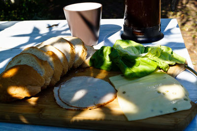 High angle view of cheese and meat with bread on cutting board at table