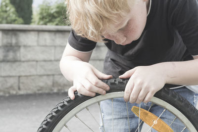 High angle view of boy repairing bicycle wheel