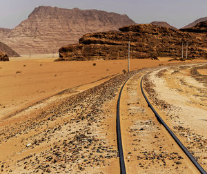 One-track railway with large rock formations in the background, in the desert of wadi rum, jordan