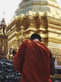 Rear view of monk standing against temple