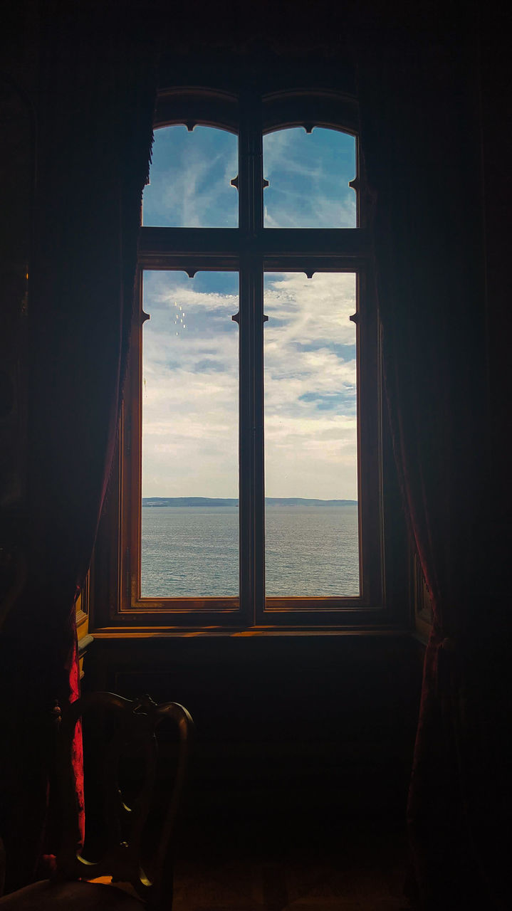 window, sky, sea, light, water, indoors, blue, darkness, nature, sunlight, cloud, architecture, interior design, looking, one person, day, house, horizon, home interior, glass, beauty in nature, room, reflection, scenics - nature, horizon over water