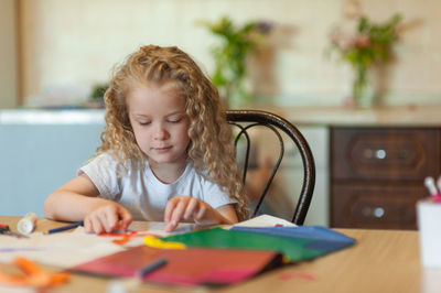 Girl looking away while sitting on table