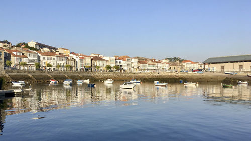 Boats in canal by houses against clear sky