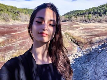 Portrait of beautiful young woman standing on mountain