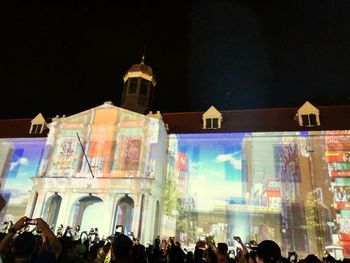 Crowd at illuminated cathedral against sky at night