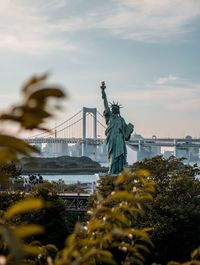 Statue of liberty in city against sky