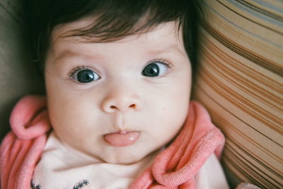 Close-up portrait of cute baby girl lying on bed at home