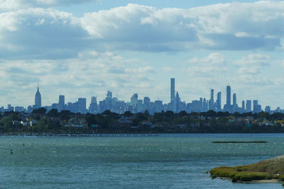 Sea and buildings in city against sky