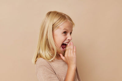 Cute girl screaming against beige background