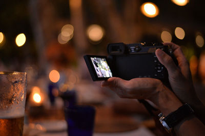 Midsection of man photographing illuminated smart phone at night