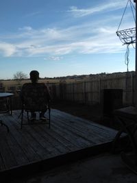 Rear view of man sitting against sky