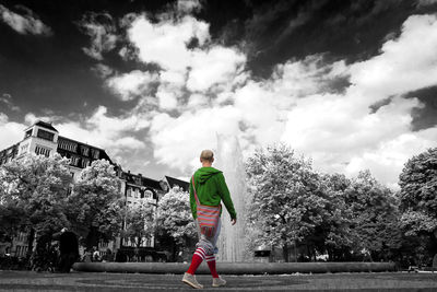 Full length rear view of boy walking against sky