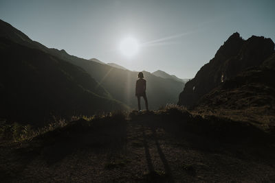 Woman standing on mountain looking at sun