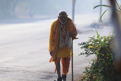 Rear view of man with umbrella walking on shore