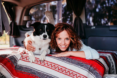 Portrait of woman with dog sitting in car