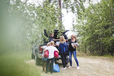 Parents with children unloading luggage from car at camping site during vacation