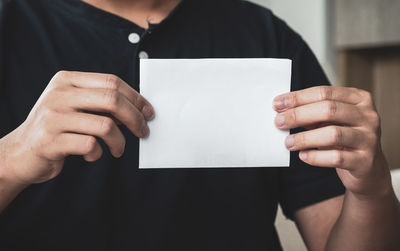 Midsection of man holding paper