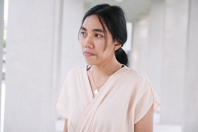 Portrait of young woman standing against wall