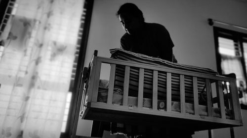 Low angle view of man sitting on window