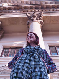 Portrait of smiling woman standing against built structure