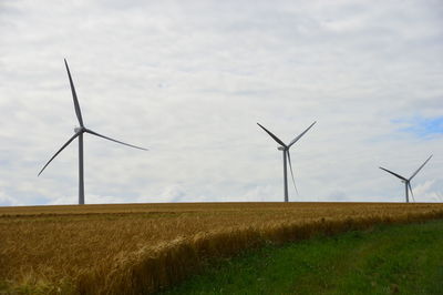Windmills on field against sky