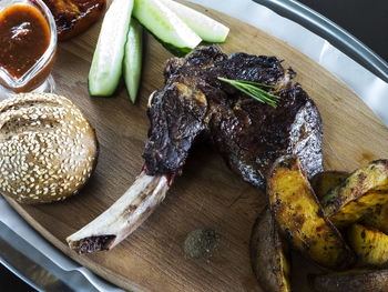 Close-up of meat and prepared potato with bread and vegetable